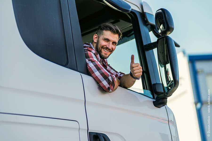 Un șofer se uită din camion și arată un like.